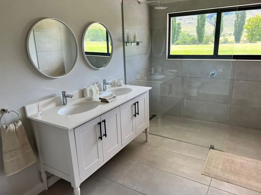 A pale stone double vanity with two basins and round mirrors